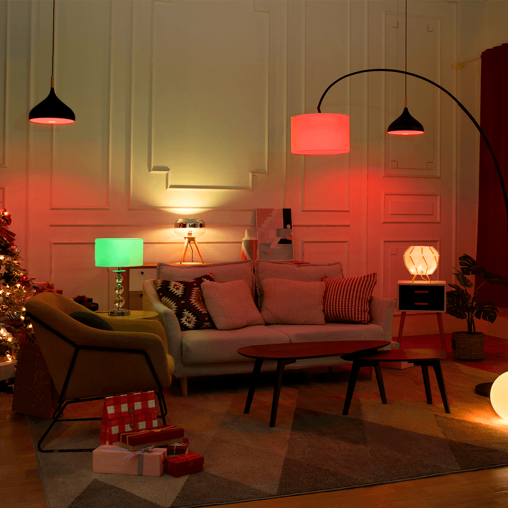 Cozy living room with colorful ambient lighting, modern furniture, and a Christmas tree with gifts.